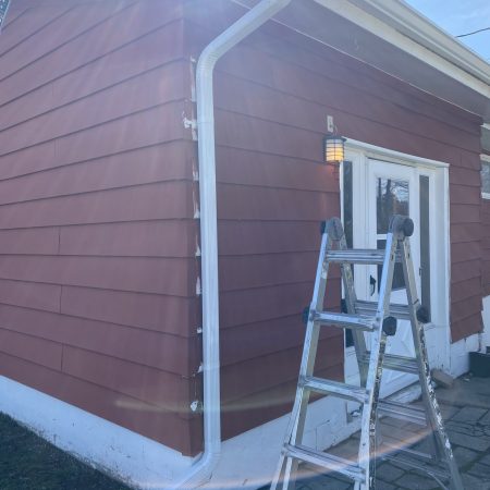 New White downspout on the side of a garage with red siding in St. Joseph, MI