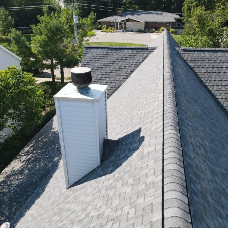 Chimney with new saddle and flashing next to CertainTeed ridge vent and Pewter ridge caps