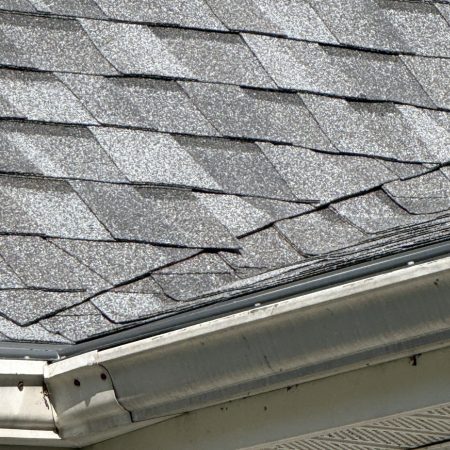 Close-up of new Pewter shingles at the eave edge above the gutter with Leaf Terminator gutter protection